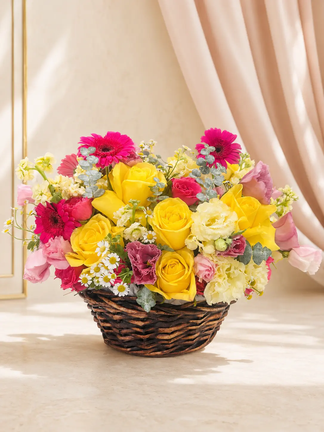 Garden-style wicker basket filled with yellow roses, hot pink gerbera daisies, lisianthus, stock and chamomile