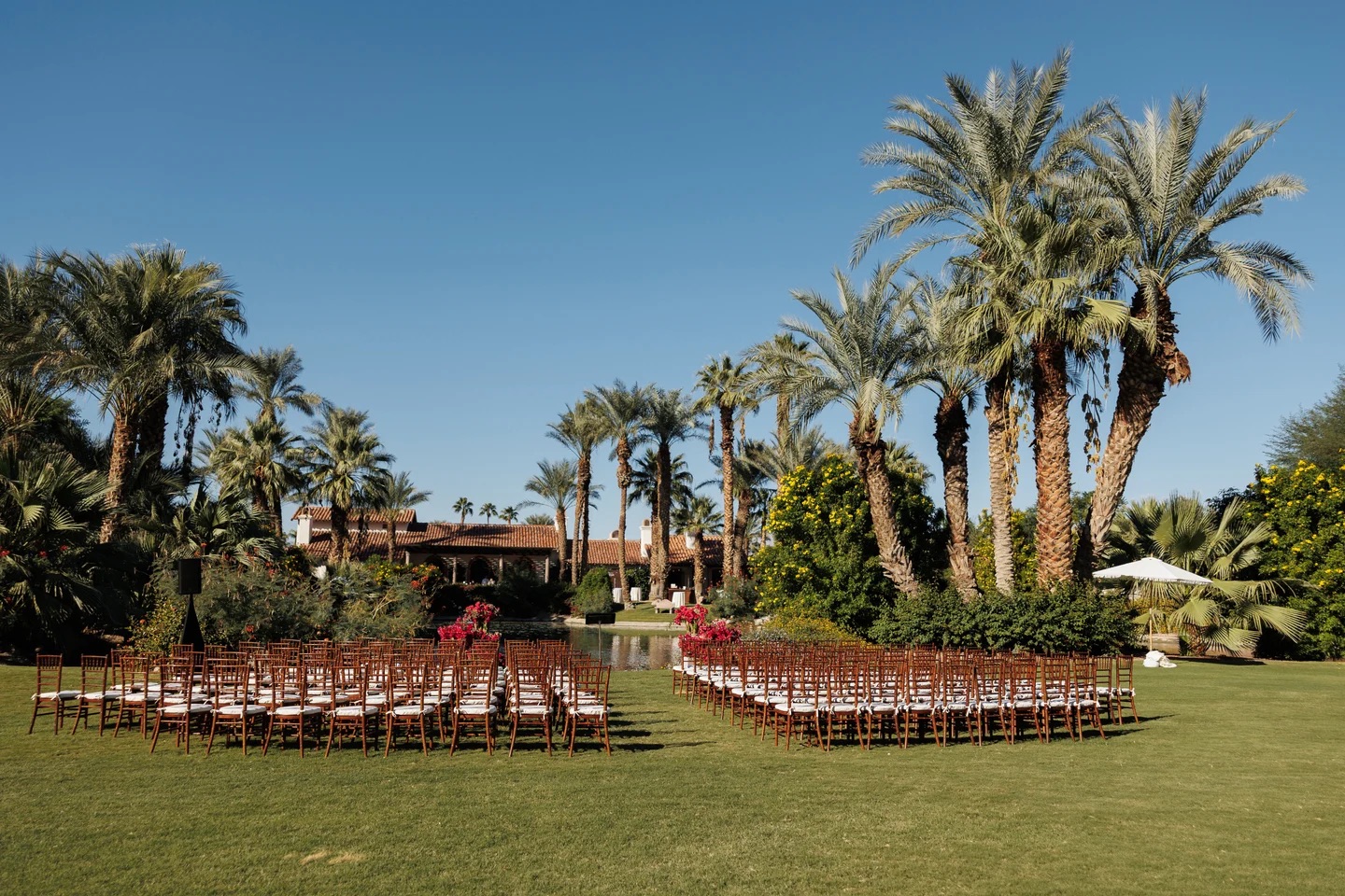 Outdoor palm-lined wedding ceremony lawn with floral accents by Bloom With Love
