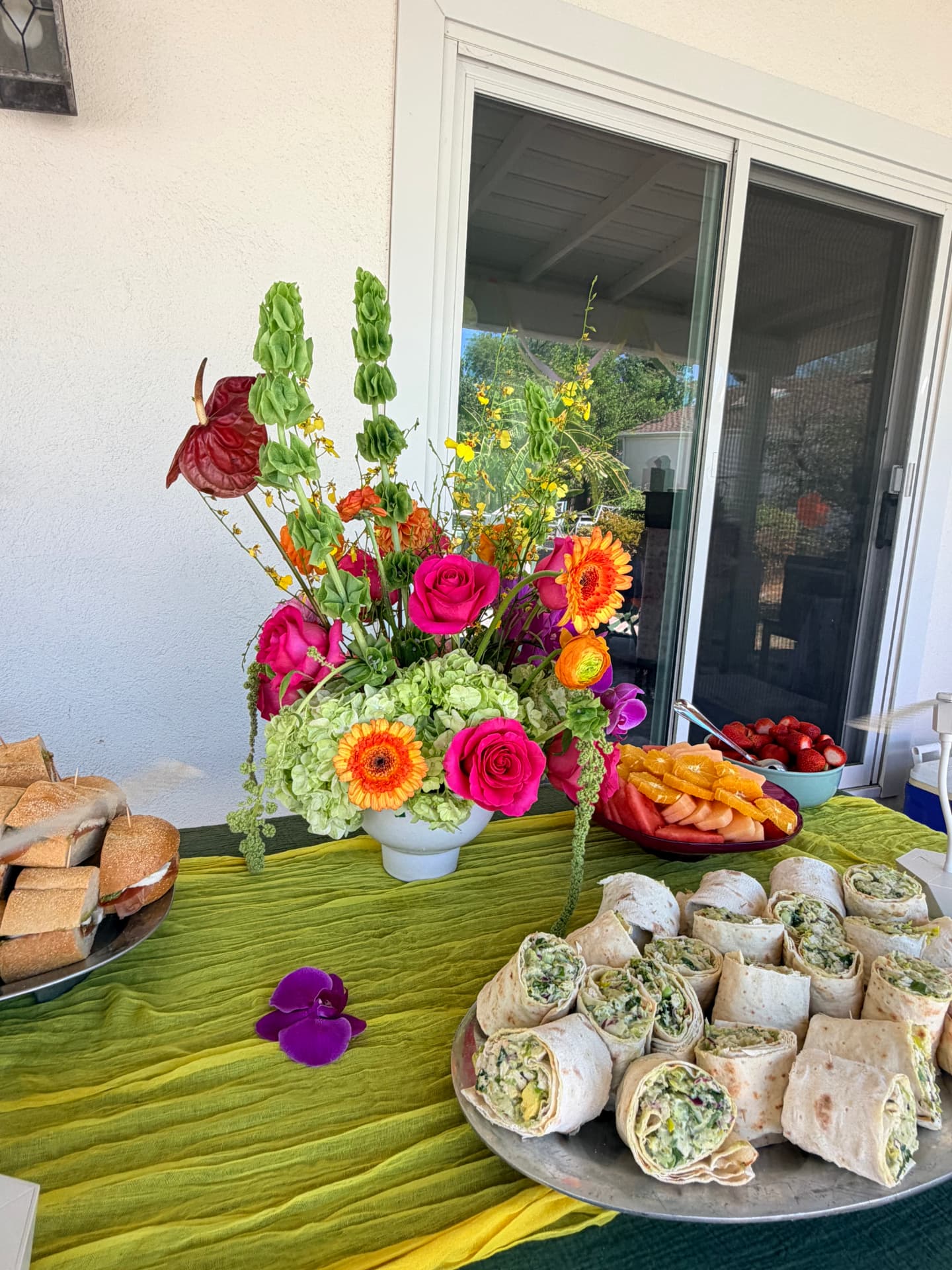 Bright garden-style floral centerpiece beside catering platters at a backyard celebration in Santa Clarita