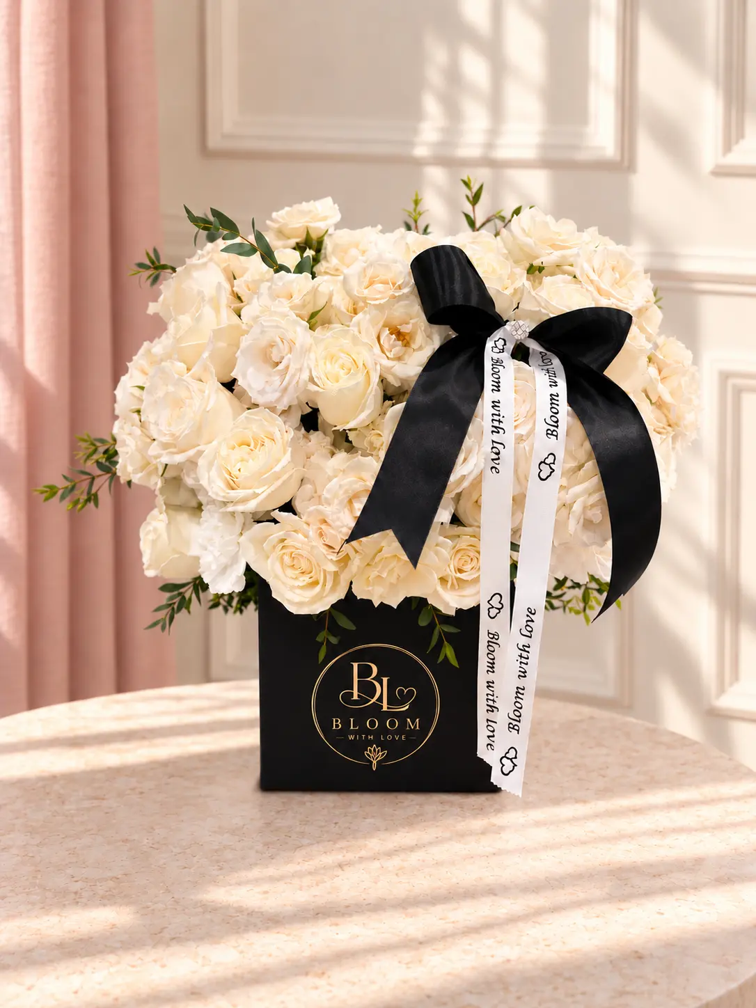 Ivory Elegance arrangement of lush ivory garden roses and white carnations in a black Bloom With Love box with a black satin bow