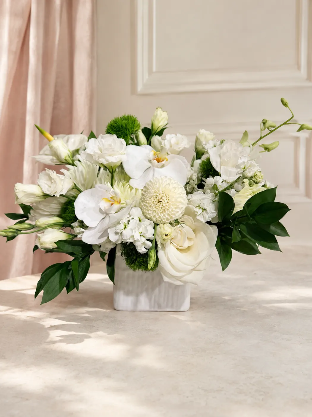 Ivory Garden Vase arrangement with white phalaenopsis orchids, white roses, dahlias and lisianthus in a ribbed white ceramic vase