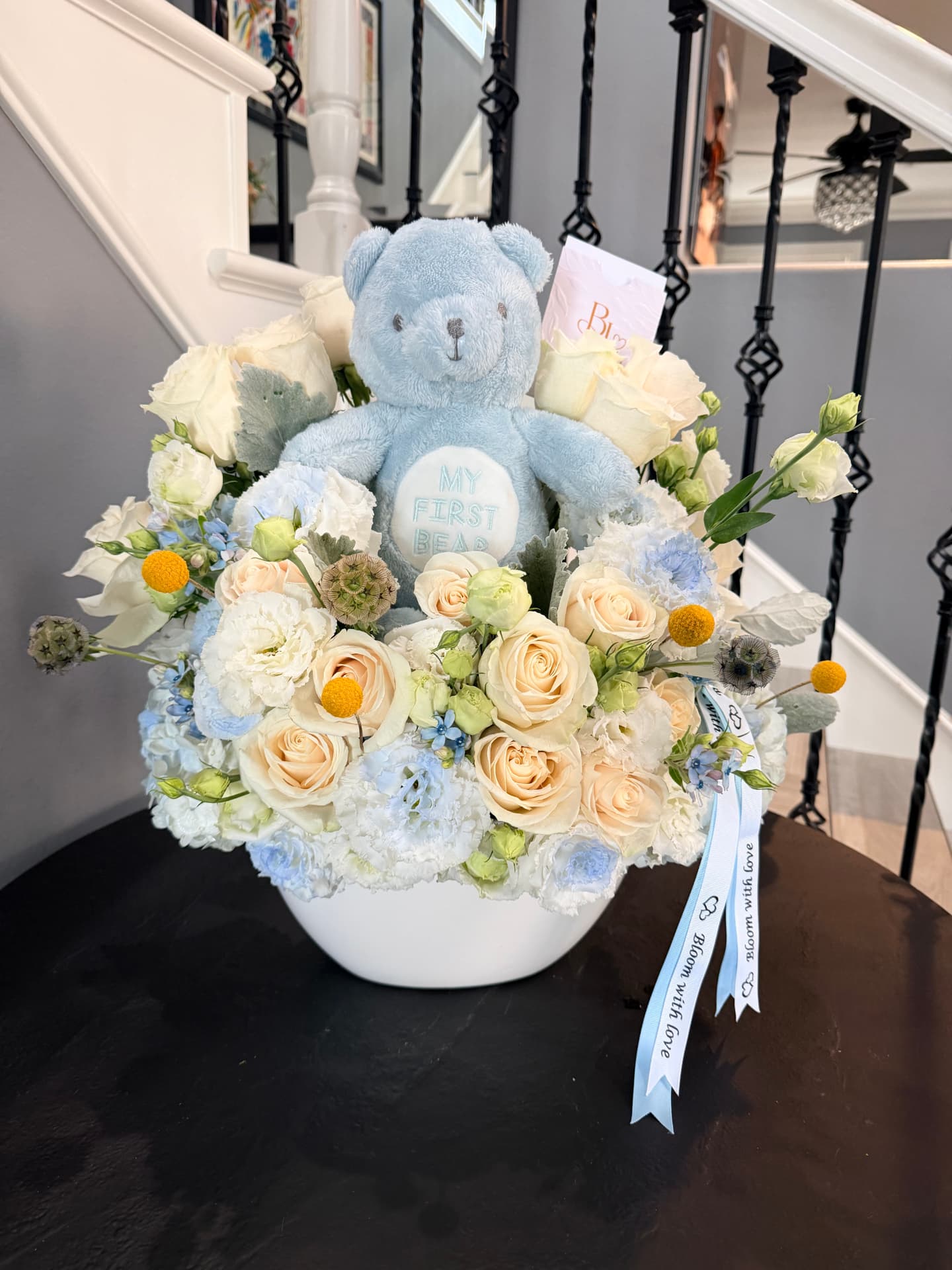 Little Love baby arrangement with a keepsake plush teddy bear nestled among ivory roses, cream blooms and baby blue accents
