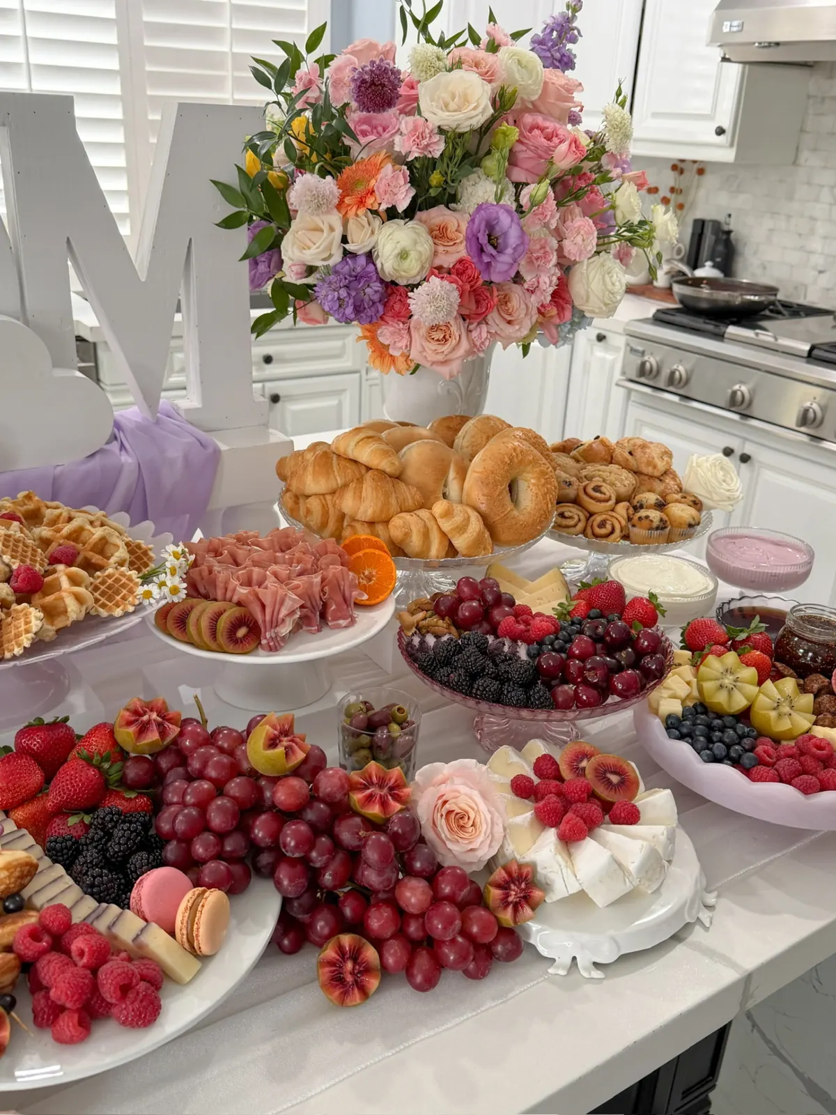 Pastel rose arrangement overlooking pastries and fruit on a brunch table