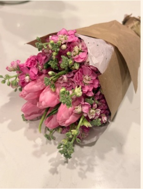 Hand-tied bouquet of pink tulips and stock wrapped in kraft paper, made by a guest at a Bloom With Love bloom bar