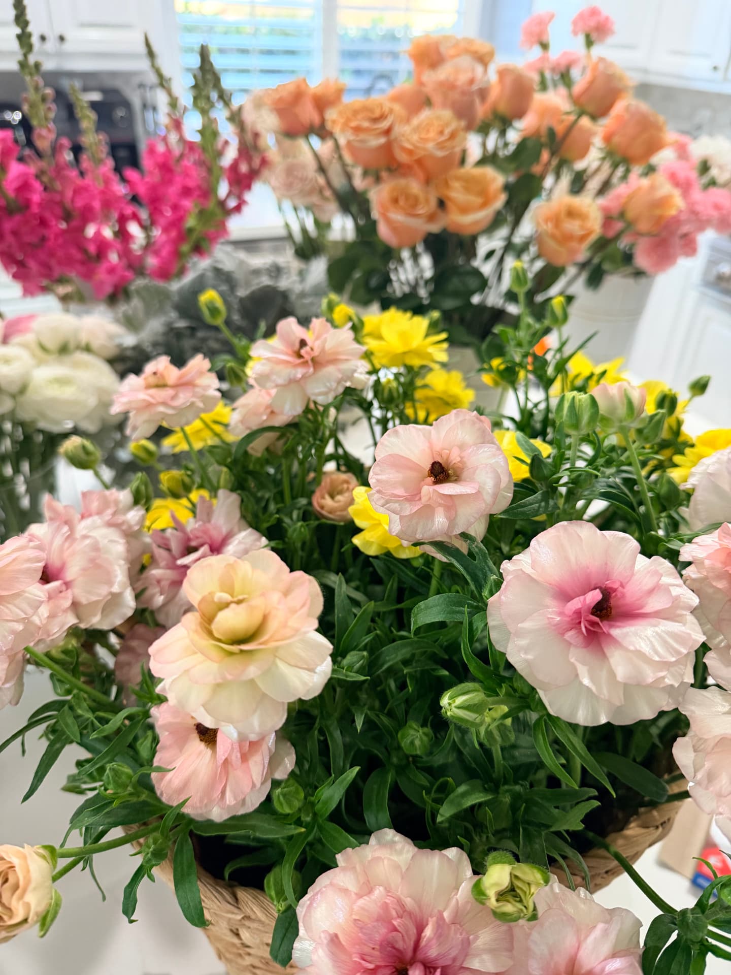 Close-up of blush ranunculus and yellow buttercups in a woven basket at a Bloom With Love bloom bar