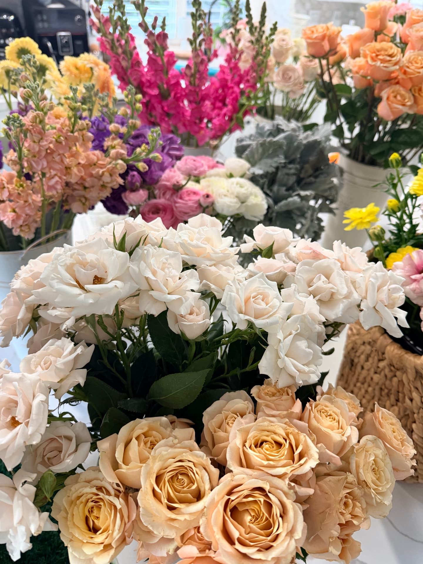 Buckets of peach roses, pink snapdragons, stock and ranunculus prepped for a Bloom With Love flower bar