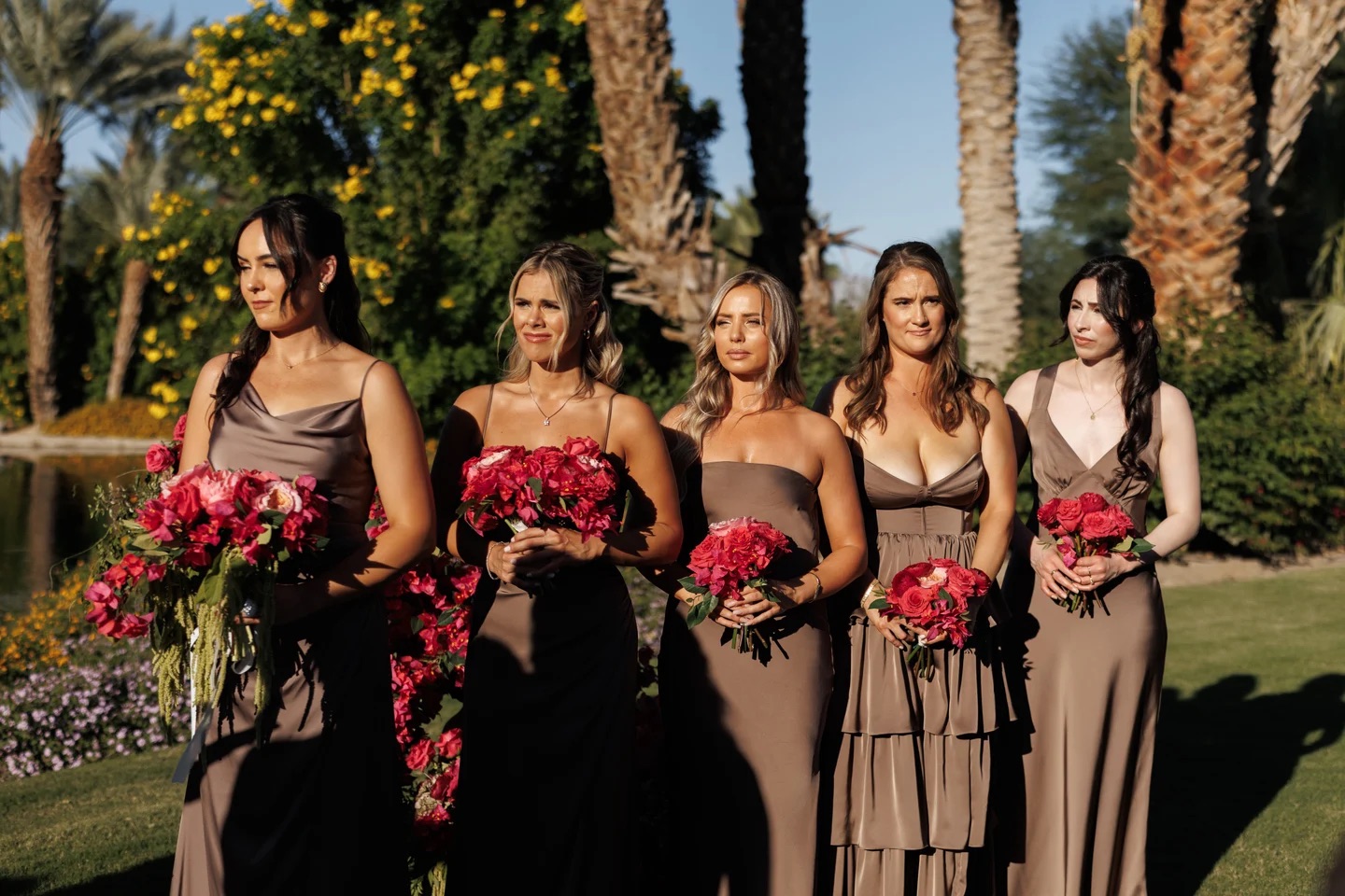 Bridesmaids in mocha gowns holding raspberry rose and bougainvillea bouquets by Bloom With Love