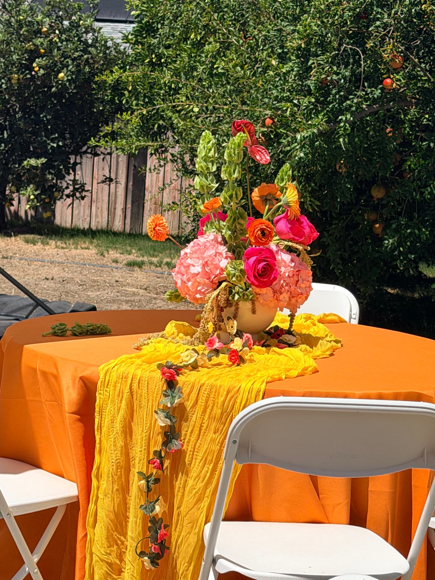 Coral hydrangea, hot pink rose and ranunculus centerpiece on a saffron gauze table runner