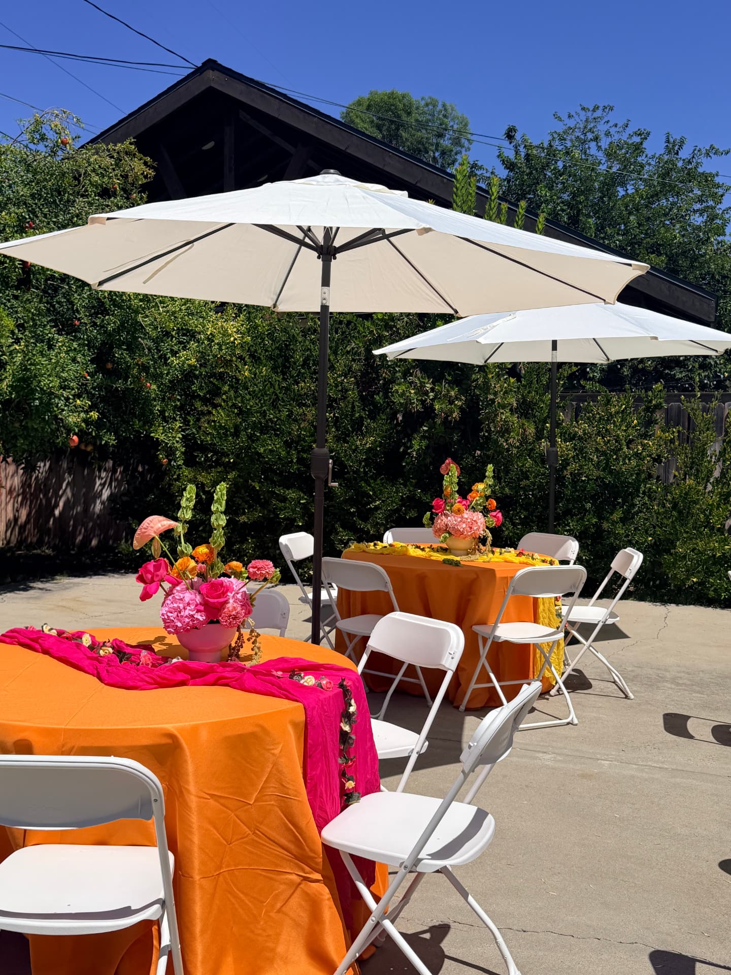 Outdoor party tables with orange linens, fuchsia runners and pink hydrangea centerpieces by Bloom With Love