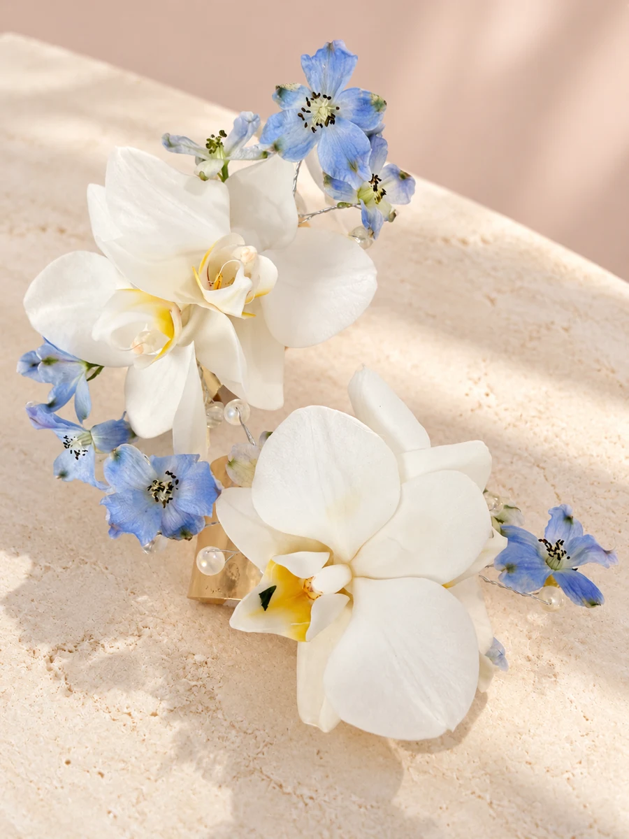 Coordinated white orchid corsage and boutonniere with blue flowers and pearl details
