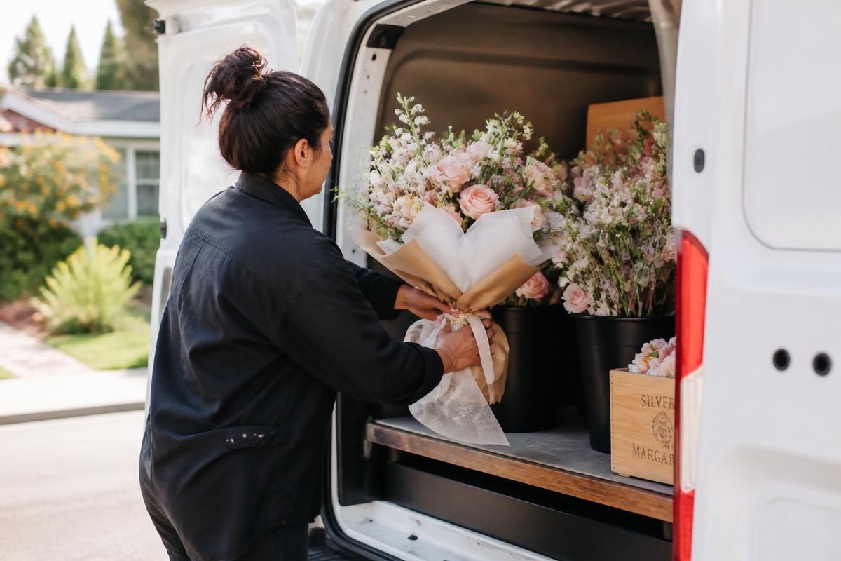 Florist loading a wrapped blush bouquet into a delivery van in a Santa Clarita neighborhood